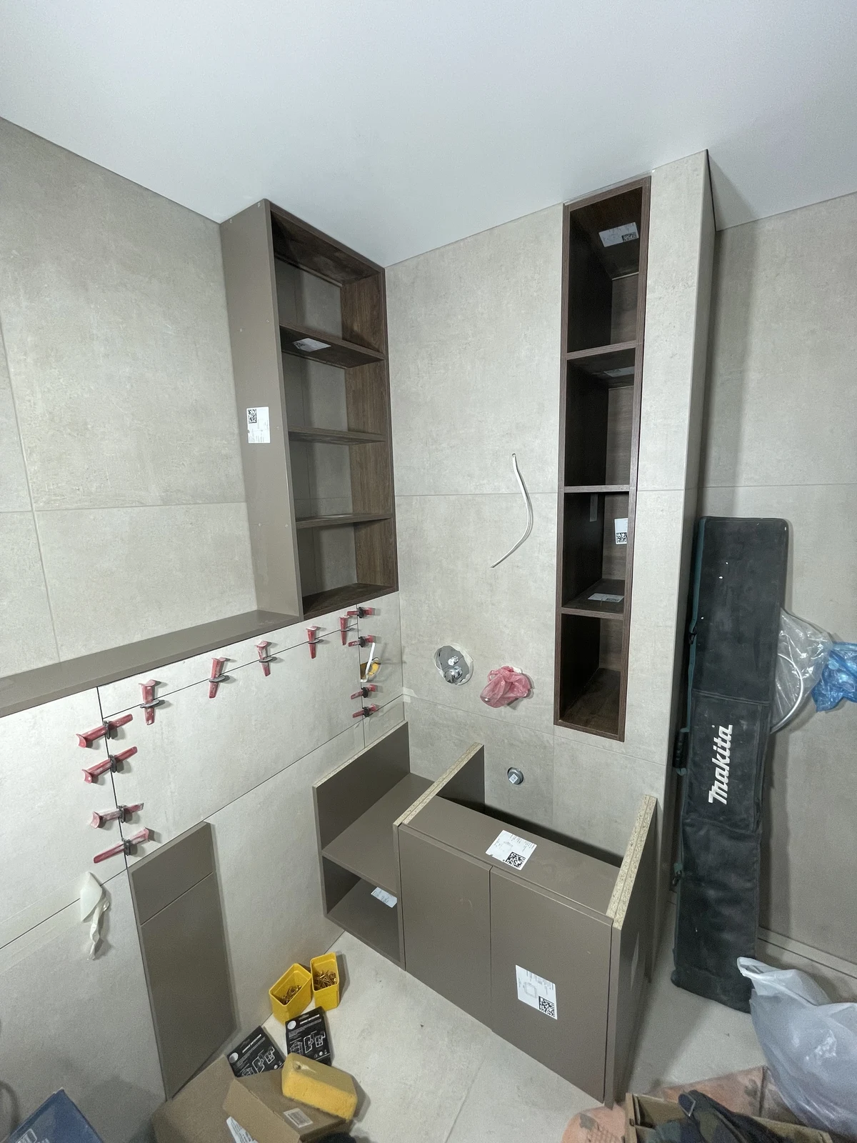 Bespoke vanity and tall storage units being fitted around the basin and mirror positions.