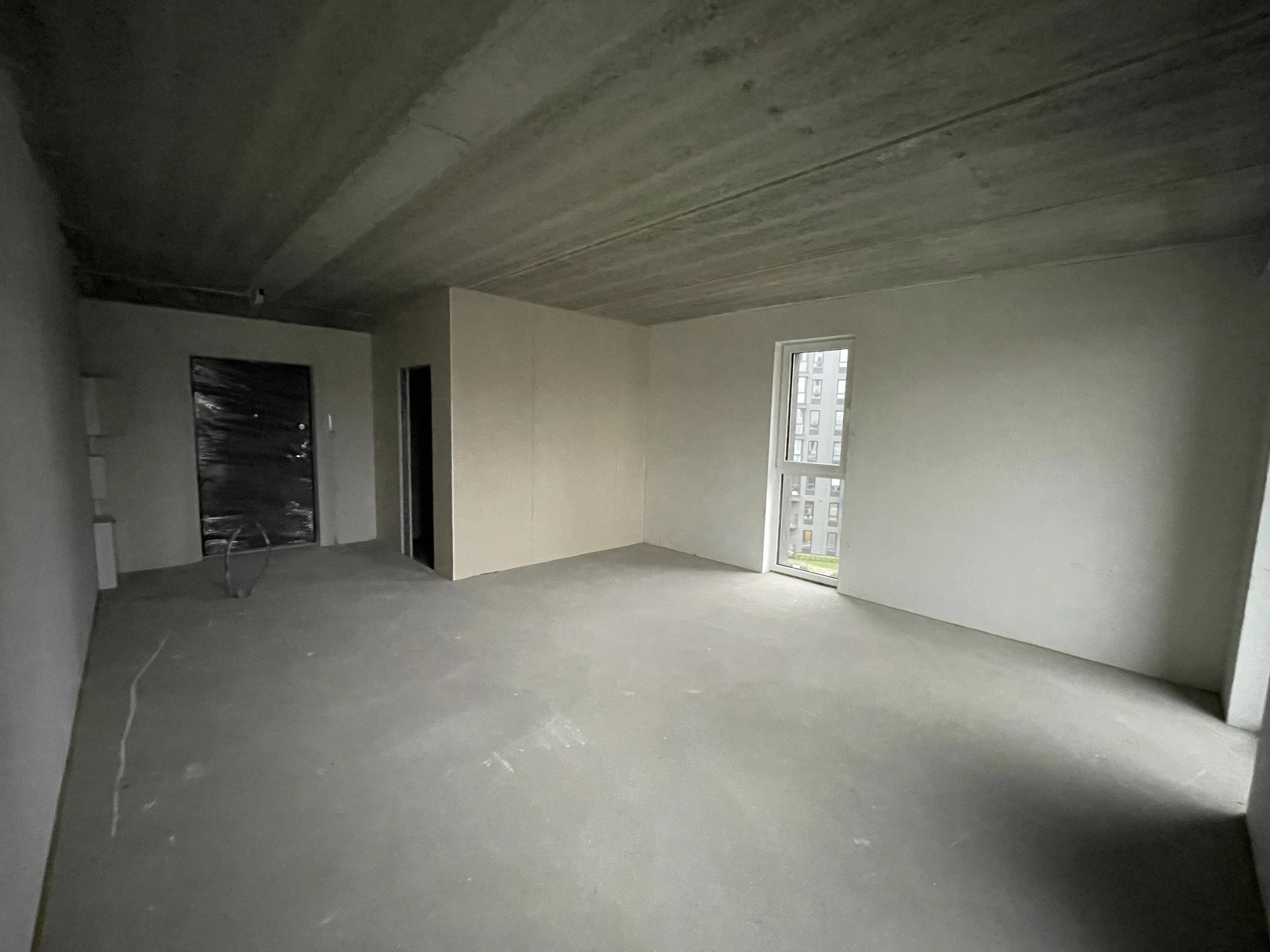 The apartment before the fit-out, looking towards the entrance, with the concrete floor and ceiling exposed.