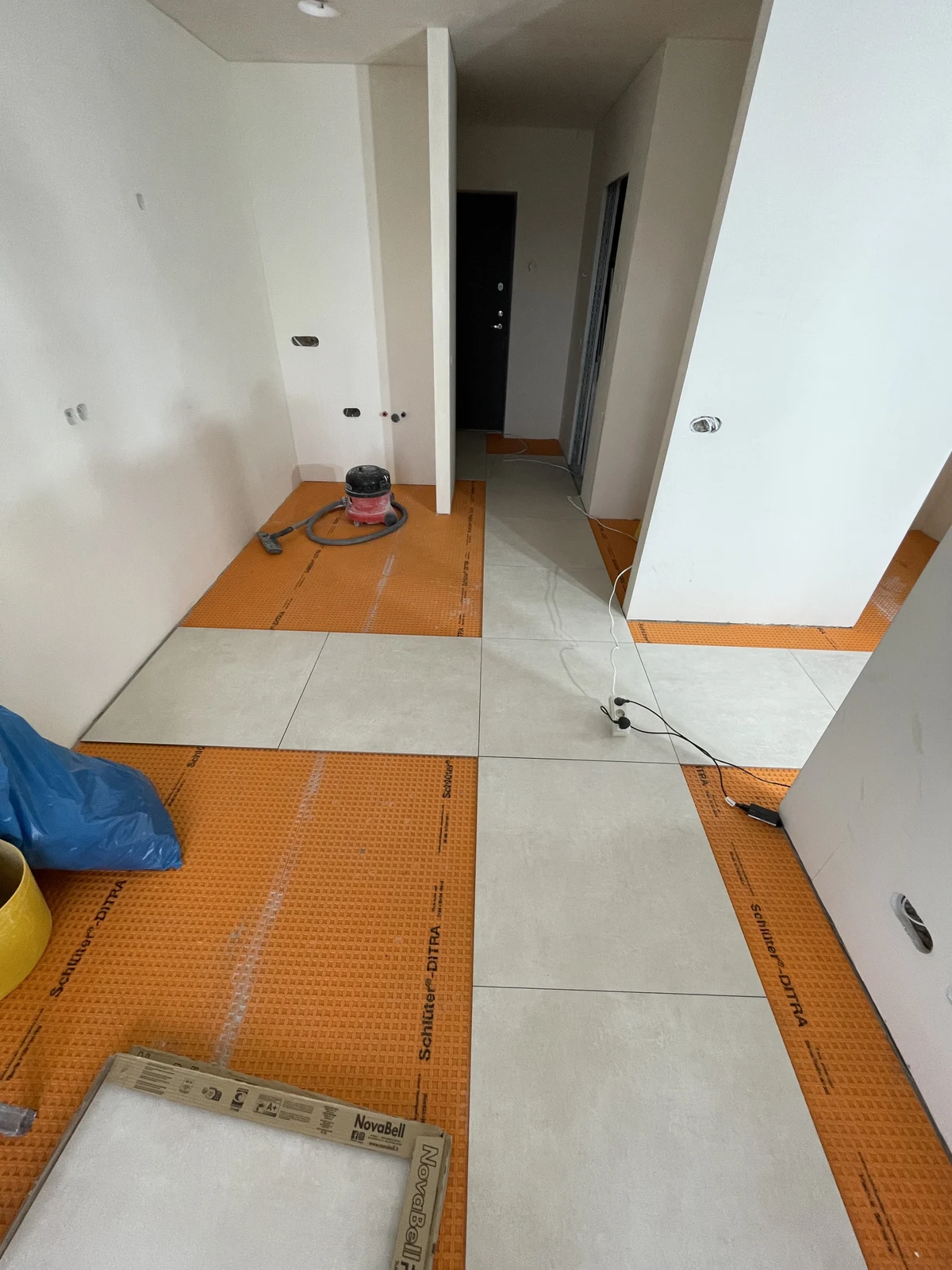 Large-format floor tiles being laid over the floor membrane.