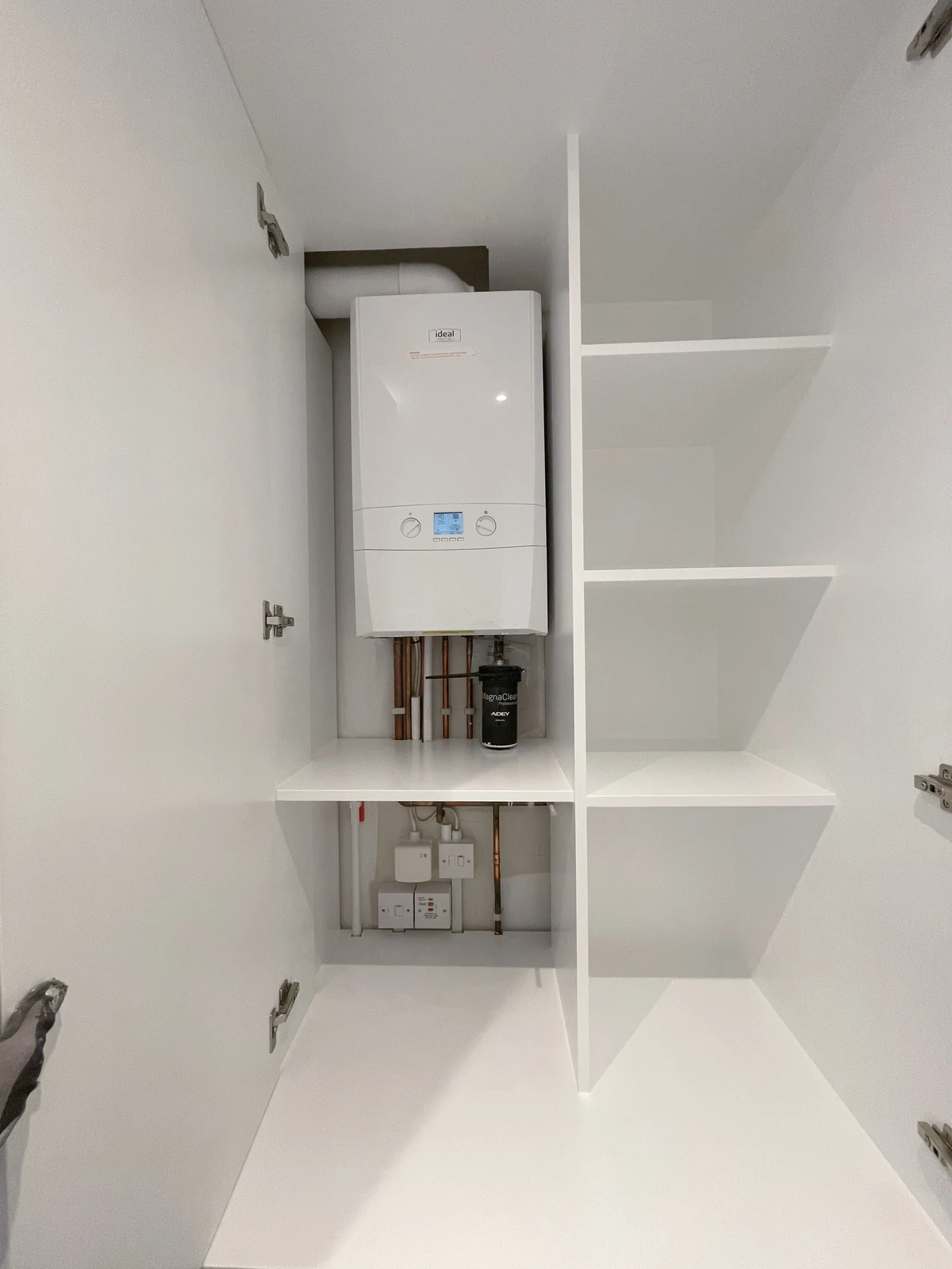 Boiler cupboard with fitted shelves and space around the pipework