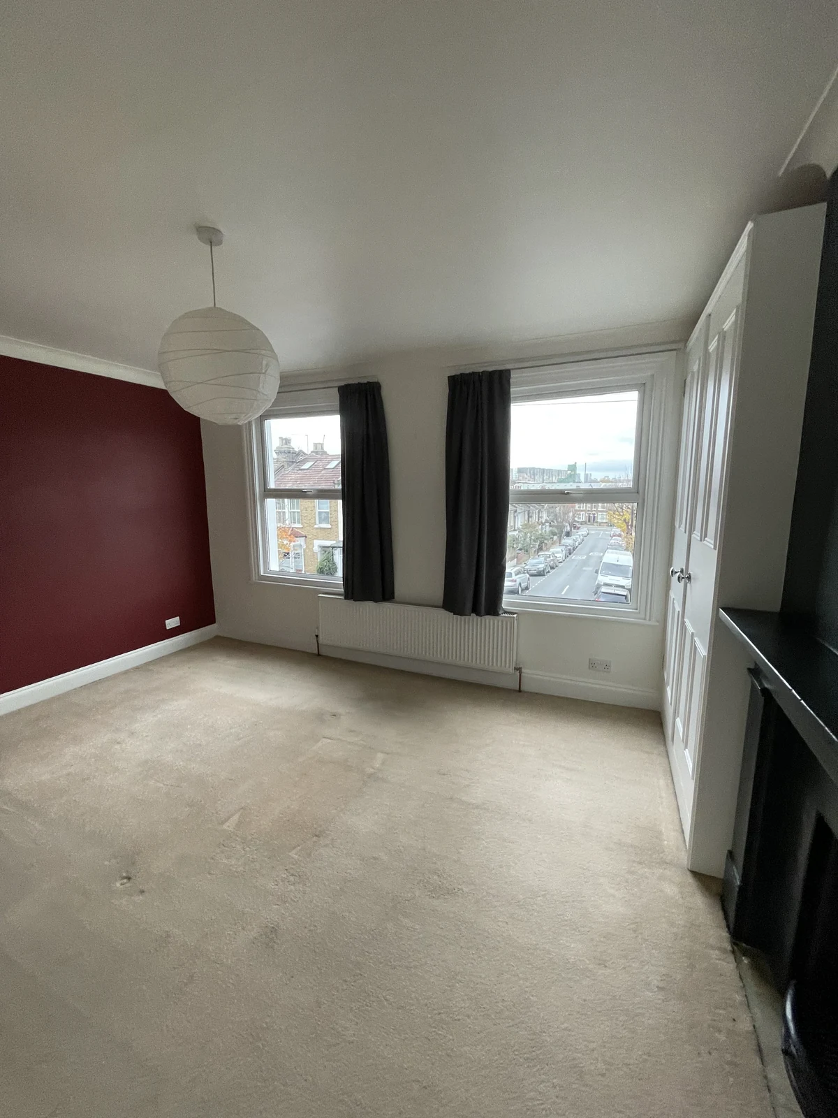 An original room with carpet, dark curtains and a coloured feature wall