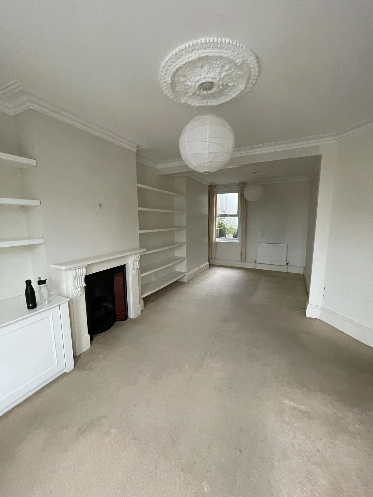 The original living room with carpet, fireplace and earlier shelving