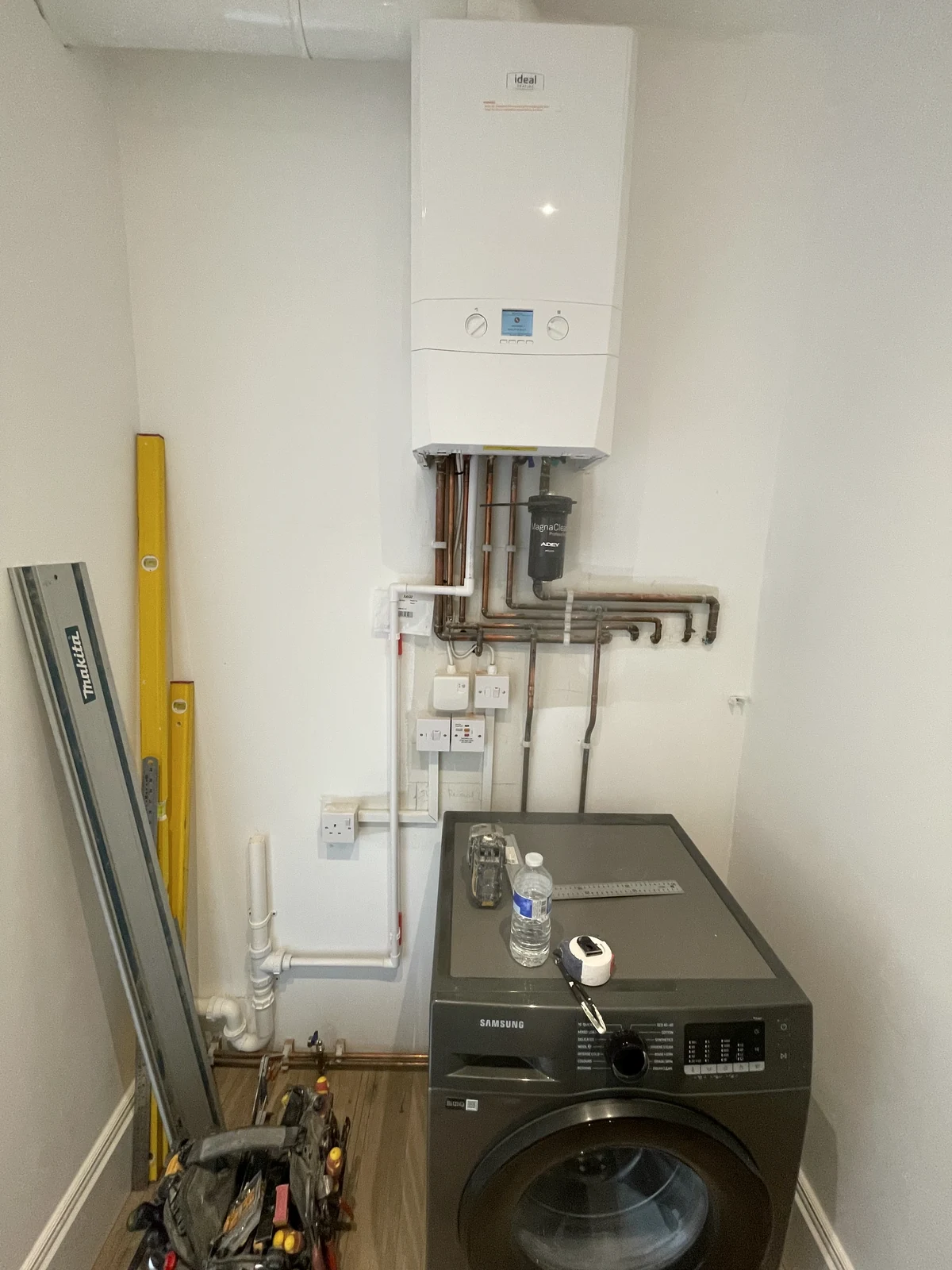 Washing machine, boiler and pipework before the fitted laundry cabinets enclosed them