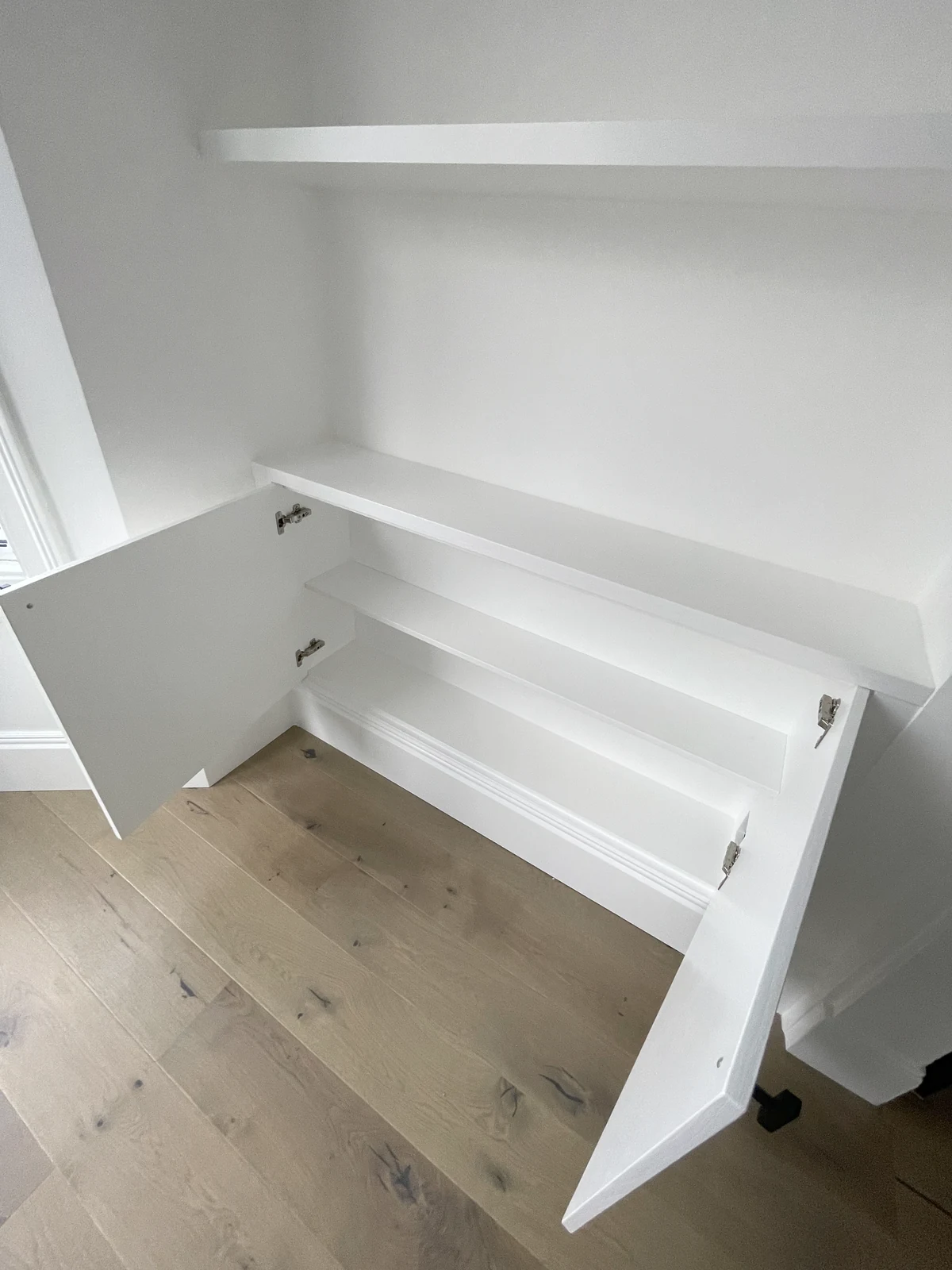 Open base cupboard showing internal shelving and concealed hinges