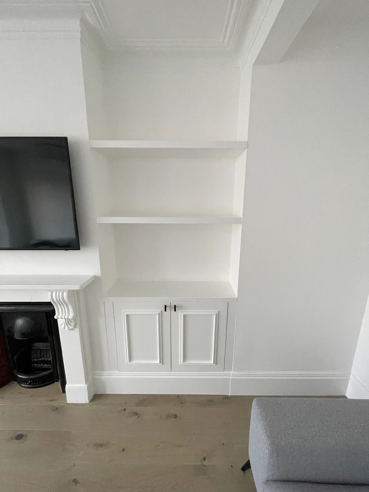 Fitted shelves and base cupboard to the right of the fireplace