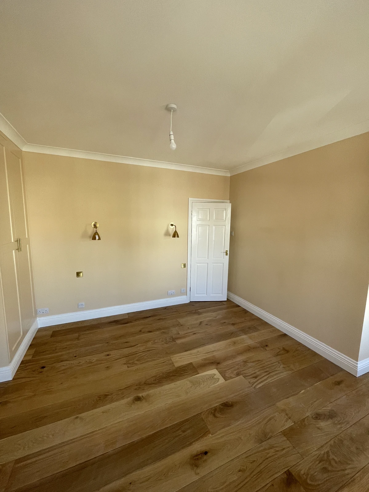 Decorated bedroom with timber flooring and wall lights.