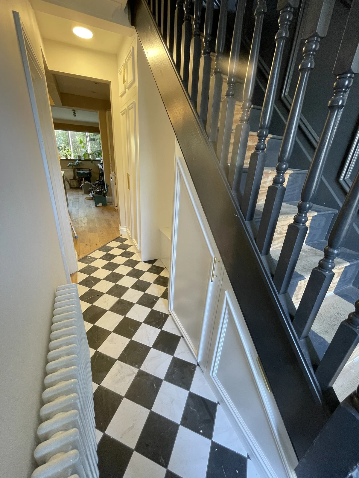 Hallway storage and stair panelling alongside the checkerboard floor.