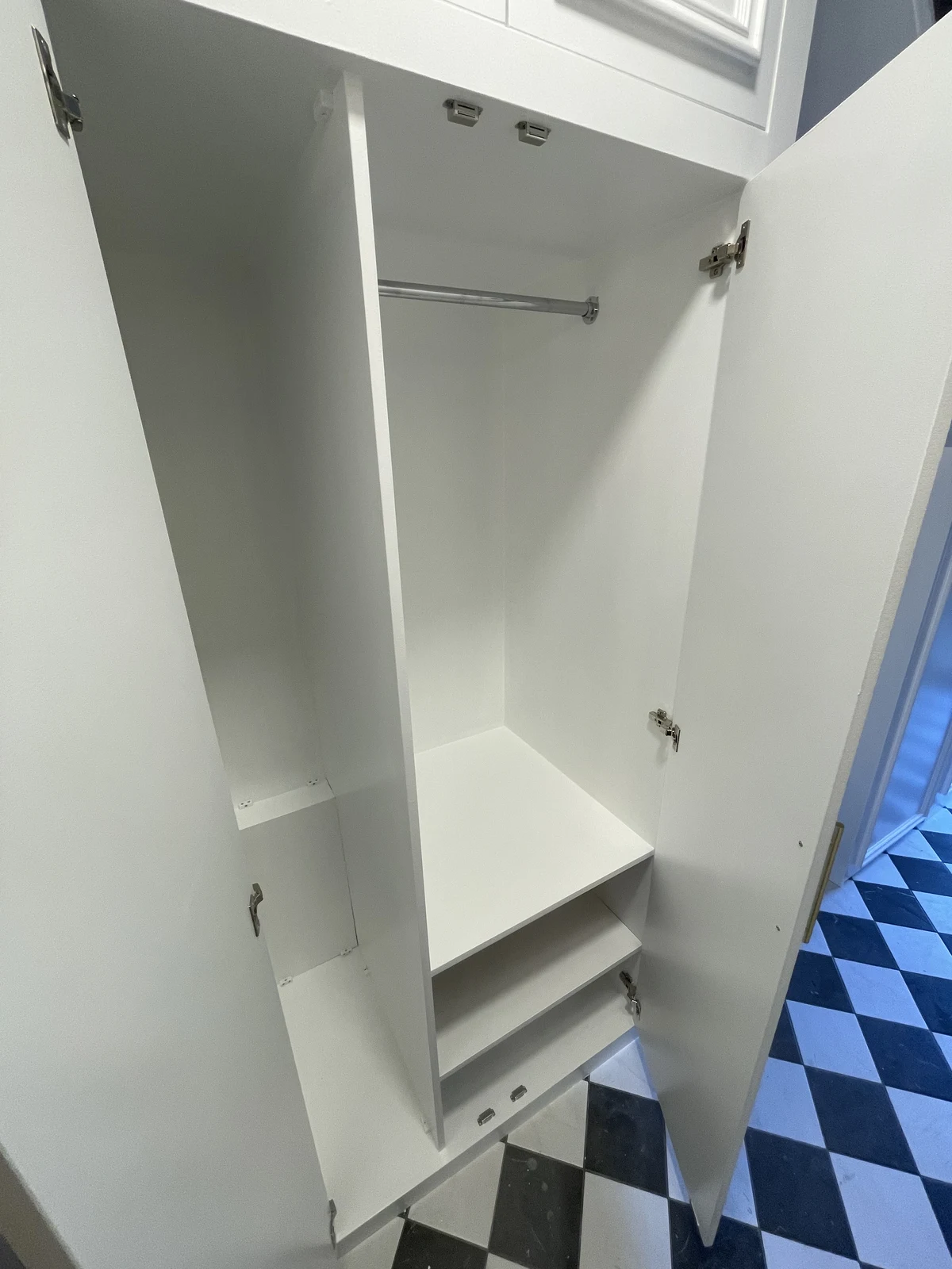 Open hallway cupboard with hanging rail and internal storage.