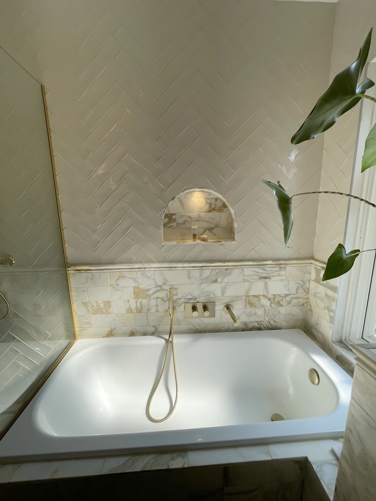 Bath and arched niche with contrasting tiled finishes.