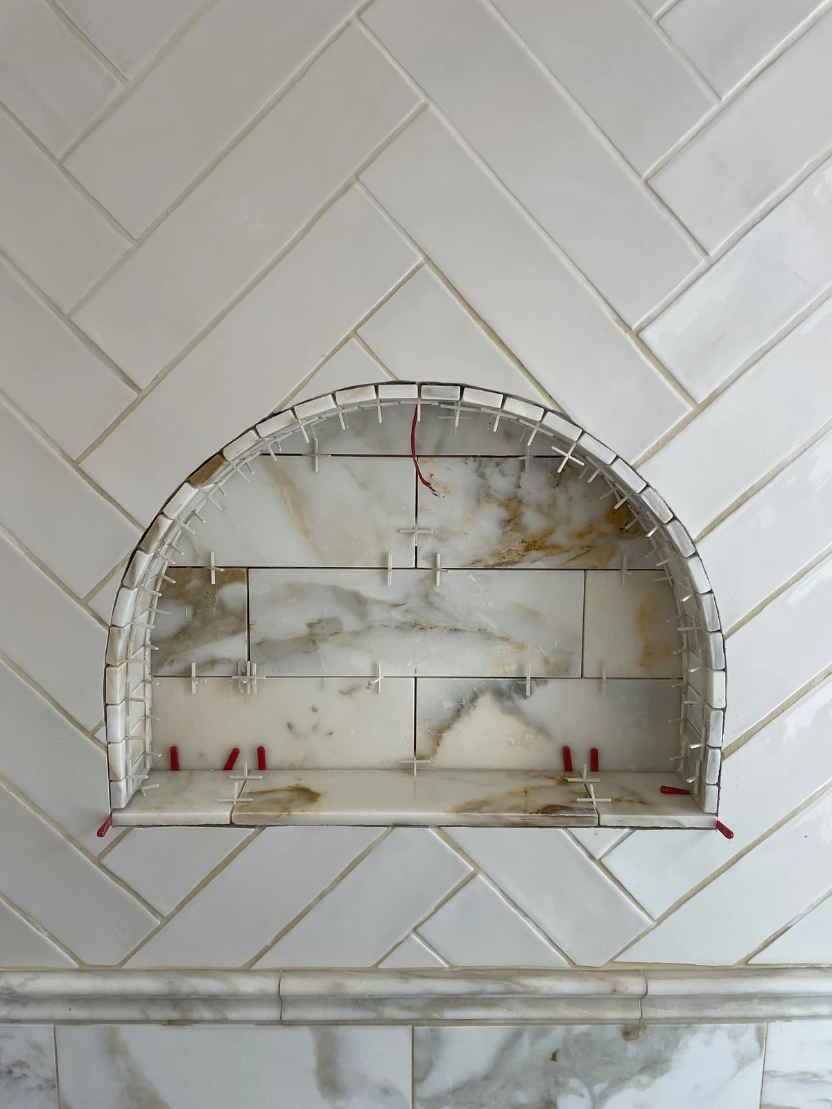 The arched bath niche during tiling, before grouting.