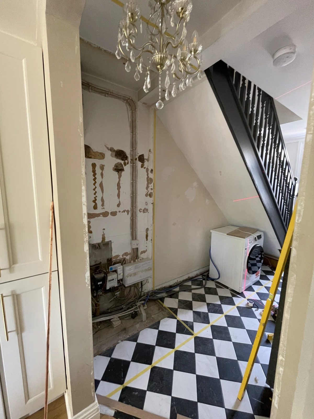 Pipework and wall preparation beside the staircase before cabinetry installation.